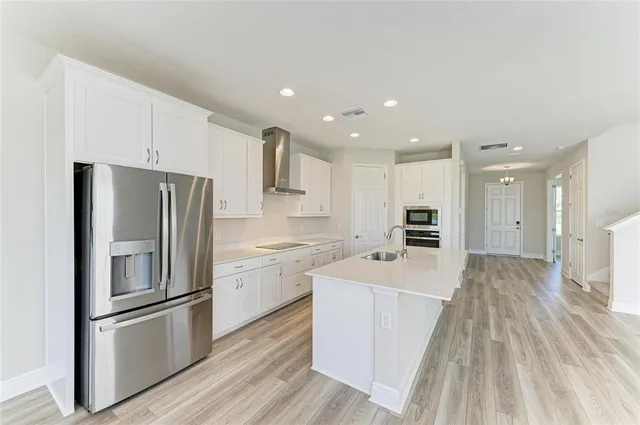 a kitchen with stainless steel appliances granite countertop a refrigerator sink and white cabinets