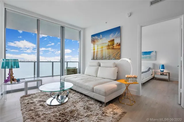 a living room with furniture a flat screen tv and a large window