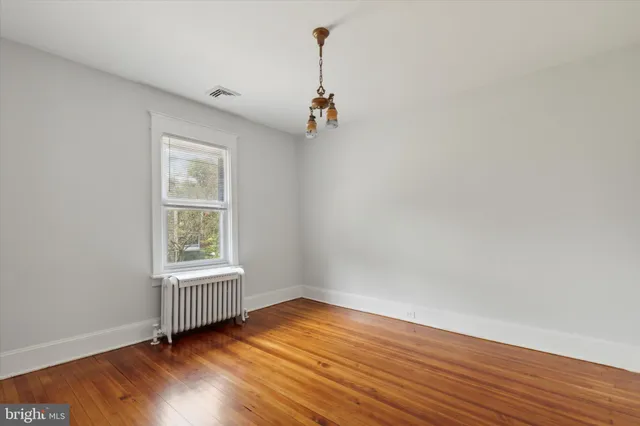 an empty room with wooden floor cabinet and windows