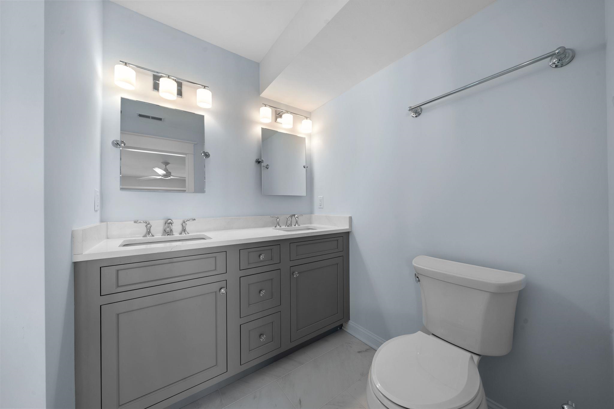 249 35th Street, Unit EAST SIDE Avalon, NJ 08202 - Photo 38 of 45 a bathroom with a toilet a sink a mirror and vanity