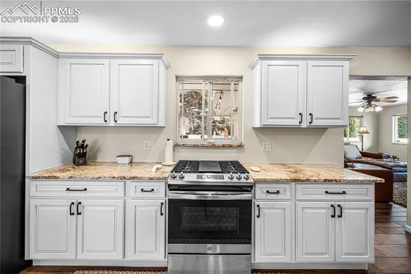 a kitchen with granite countertop white cabinets and appliances