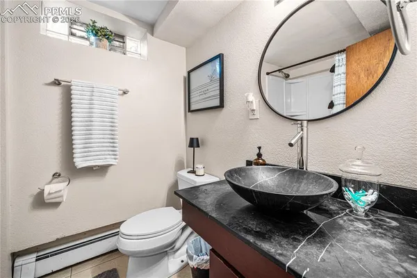 a bathroom with a granite countertop toilet a sink and a mirror