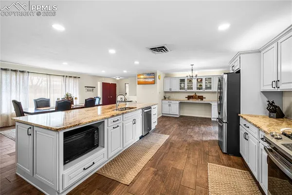 a kitchen with stainless steel appliances granite countertop a kitchen island a stove and a sink