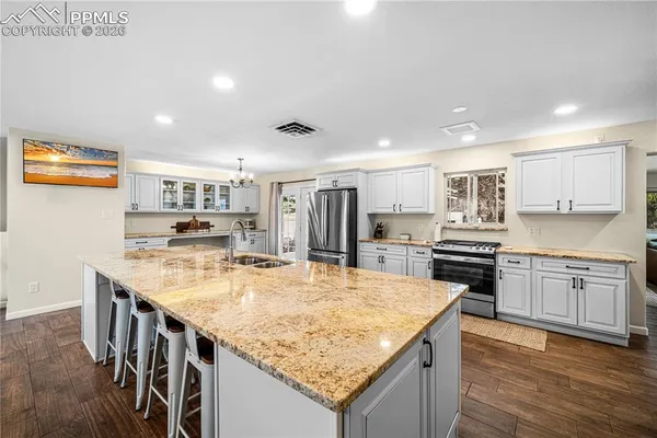 a kitchen with stainless steel appliances granite countertop a kitchen island a stove and a sink