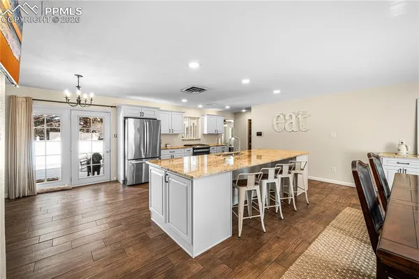 a kitchen with stainless steel appliances kitchen island granite countertop a table chairs sink and cabinets