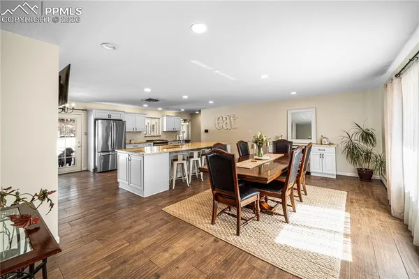 a living room with stainless steel appliances kitchen island granite countertop furniture and a dining table with wooden floor