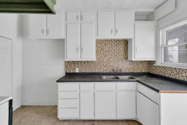 a kitchen with granite countertop white cabinets and sink