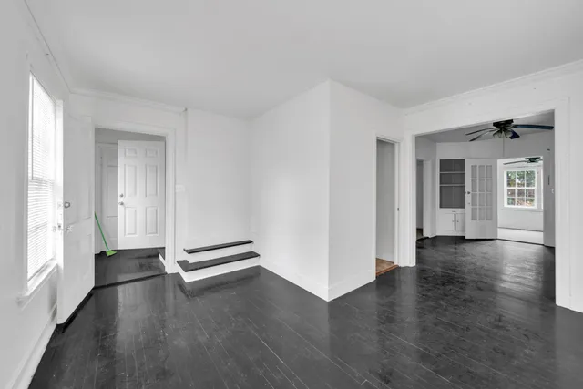 an empty room with wooden floor and windows