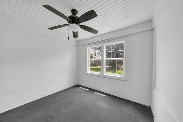 an empty room with a ceiling fan and windows