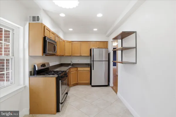 a kitchen with a refrigerator a stove top oven and cabinets