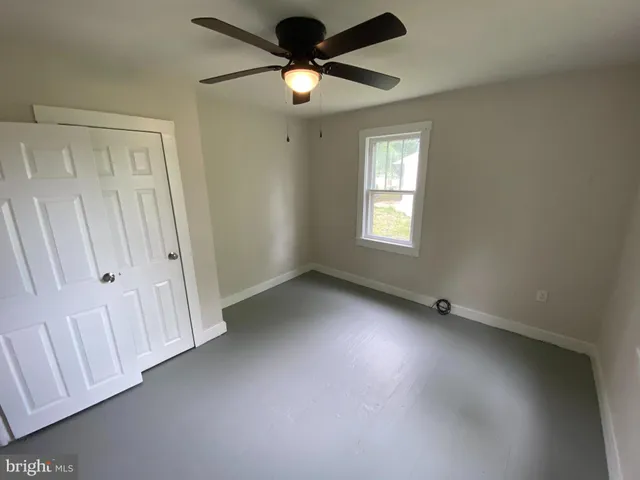 an empty room with windows and fan