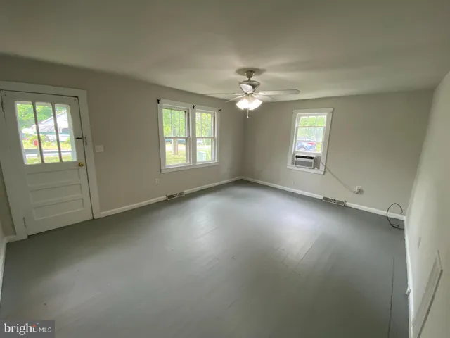 an empty room with windows and fan