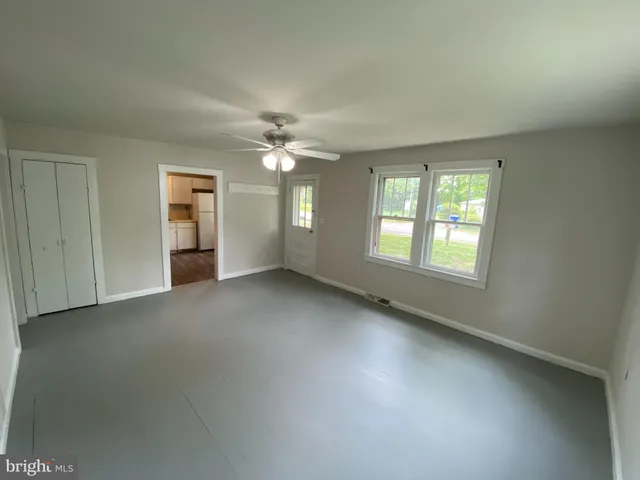 an empty room with chandelier fan and windows