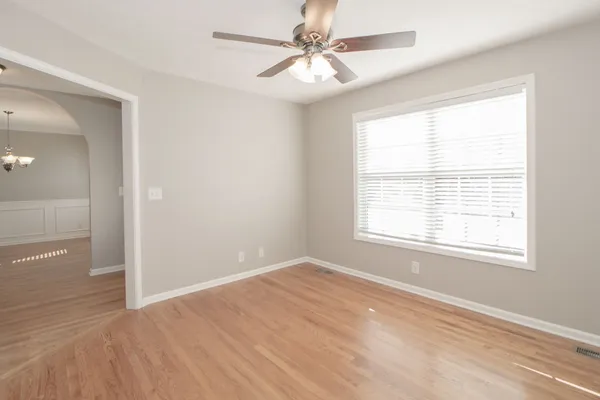 an empty room with wooden floor chandelier fan and closet area