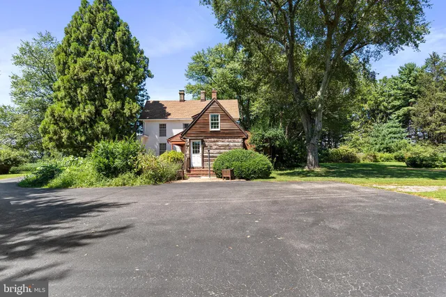 a view of a house with a small yard and large trees