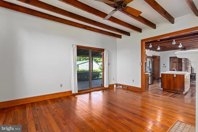 a view of an empty room with wooden floor fireplace and a window
