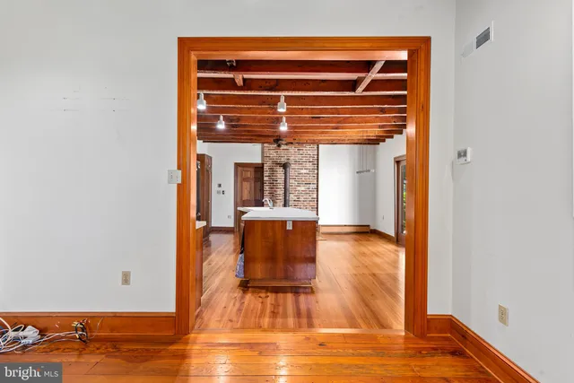 a view of an empty room with wooden floor and windows