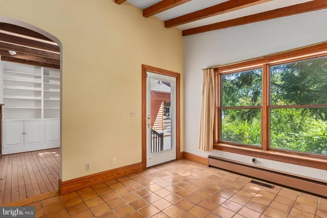 a view of an empty room with wooden floor fireplace and a window