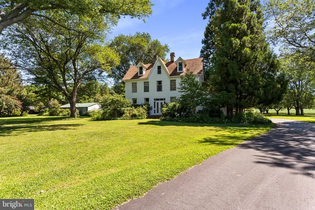 a view of swimming pool in front of house with yard and large trees