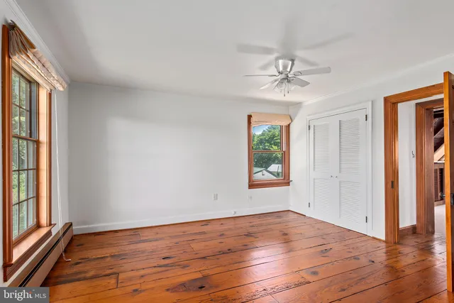 a view of a hallway with wooden floor and a bathroom