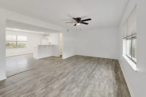 a view of empty room with wooden floor and ceiling fan
