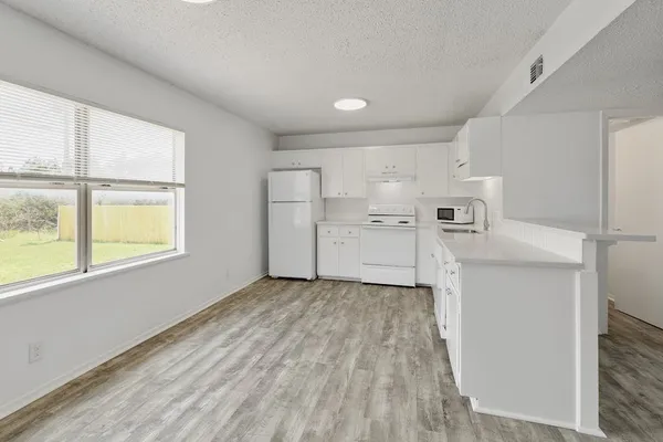 a kitchen with white cabinets and wooden floor