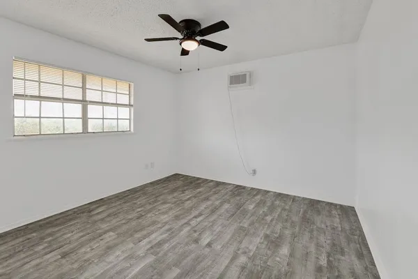 an empty room with a window and a fan