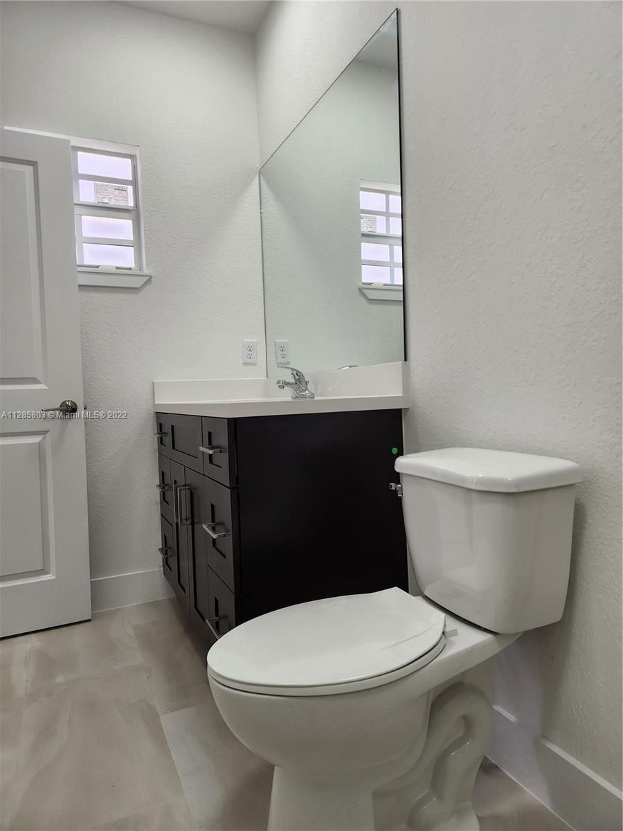 22065 Miami Avenue Miami, FL 33170 - Photo 16 of 27 a bathroom with a toilet a sink and mirror