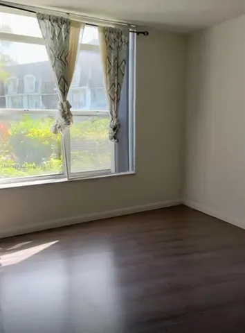 a view of a room with wooden floor and a window