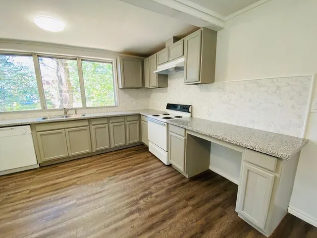 a kitchen with stainless steel appliances granite countertop a sink cabinets and wooden floor