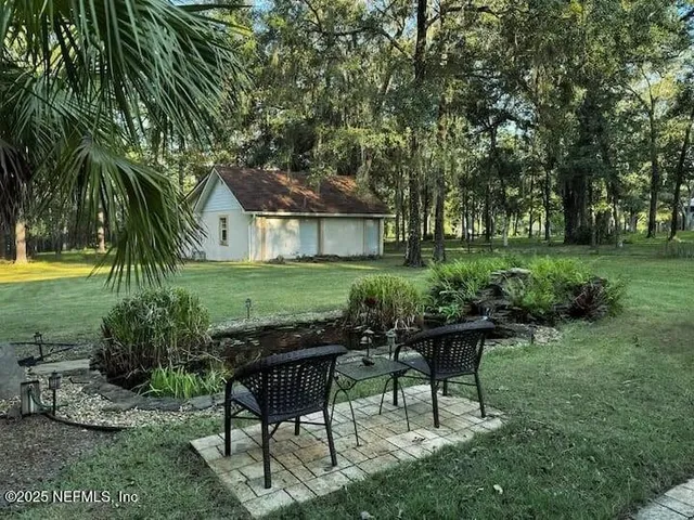 a view of a backyard with table and chairs potted plants and large tree