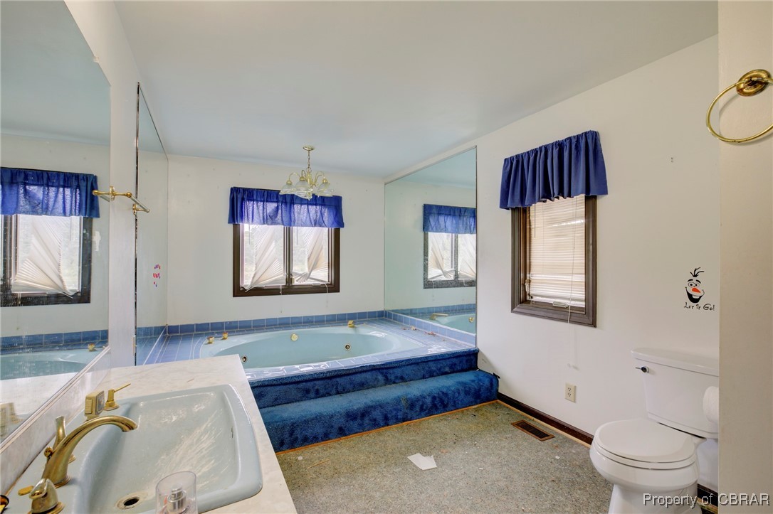 2488 Winfred Road Hayes, VA 23072 - Photo 24 of 25 Bathroom with tiled tub, toilet, sink, and a healthy amount of sunlight