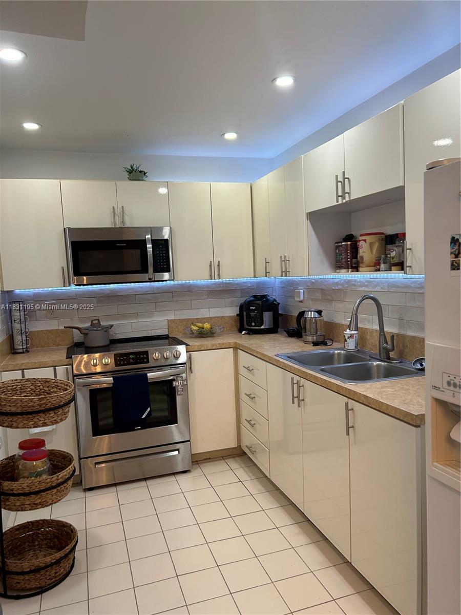 8251 Northwest 8th Street, Unit 214 Miami, FL 33126 - Photo 3 of 19 a kitchen with stainless steel appliances granite countertop a stove a sink and a microwave