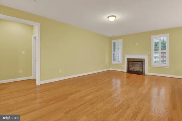 a view of empty room with wooden floor and fireplace