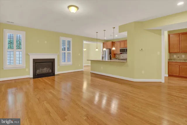a view of a livingroom with wooden floor and a kitchen