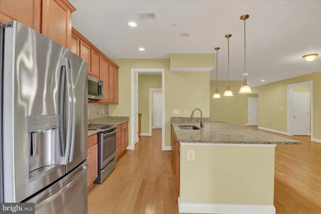 a kitchen with stainless steel appliances granite countertop a refrigerator a sink a stove and a wooden floors