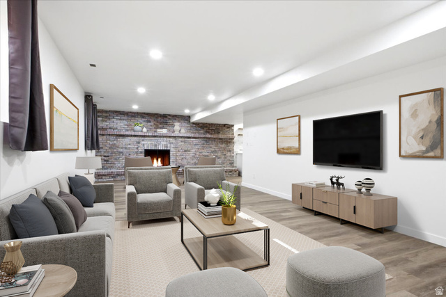 1676 East 11245 South Sandy, UT 84092 - Photo 21 of 34 Spacious living area featuring a prominent brick-clad fireplace, recessed lighting, wood-finish flooring, and a neutral color palette. This picture is virtually staged.