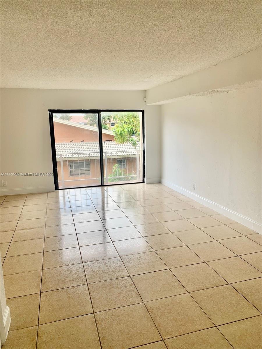 a view of an empty room with a floor to ceiling window and a garage
