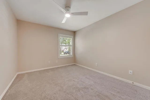 an empty room with windows and ceiling fan