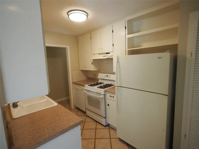 a kitchen with a refrigerator a stove top oven and a cabinets