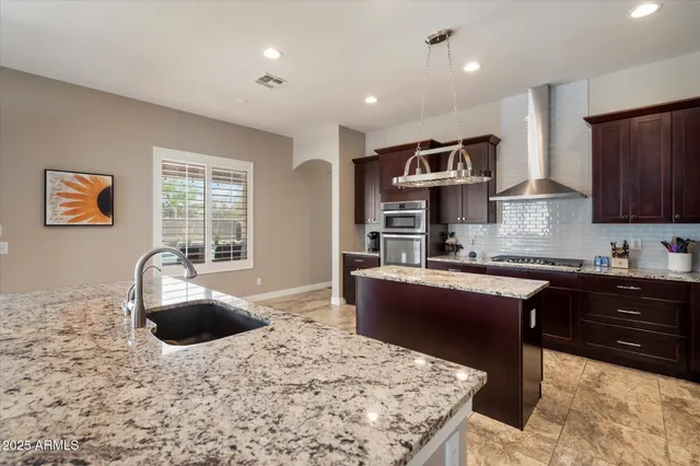 a kitchen with stainless steel appliances kitchen island granite countertop a sink dishwasher stove and refrigerator