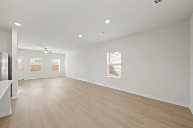 an empty room with wooden floor and windows
