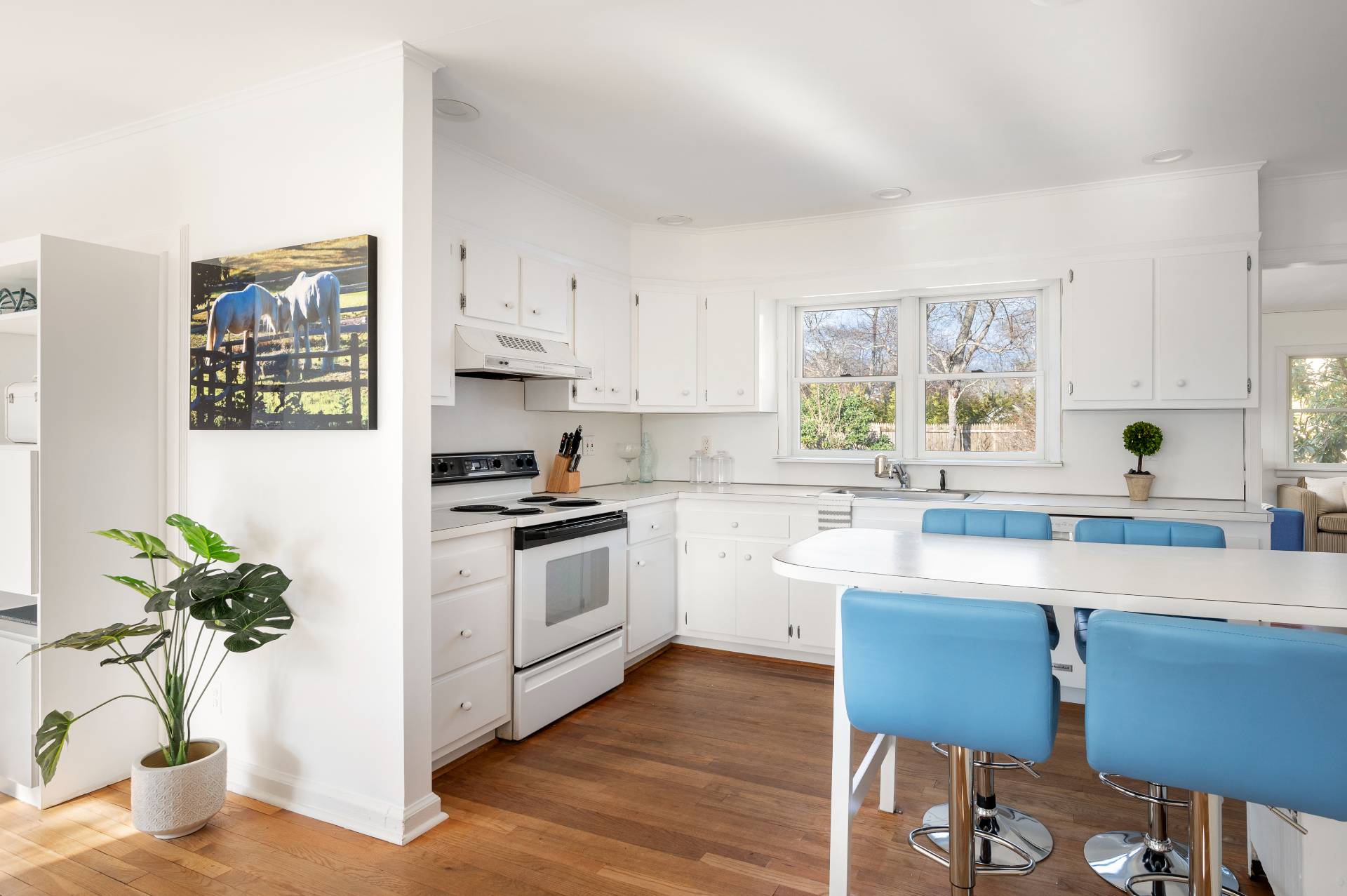 25 Lynncliff Road Hampton Bays, NY 11946 - Photo 8 of 24 a kitchen with stainless steel appliances a sink a stove a refrigerator cabinets and wooden floor