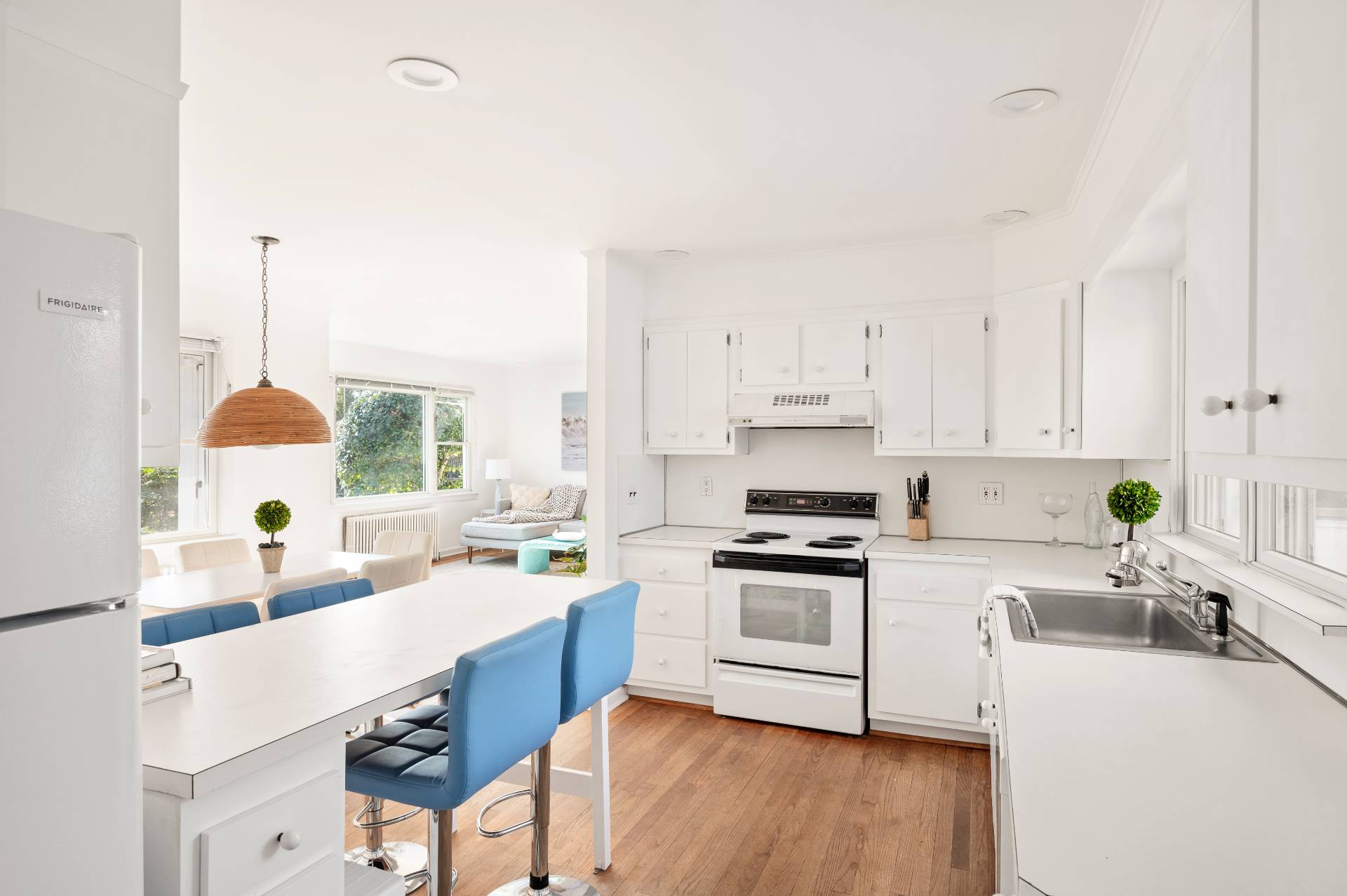 25 Lynncliff Road Hampton Bays, NY 11946 - Photo 9 of 24 a kitchen with a sink a stove a refrigerator and white cabinets with wooden floor