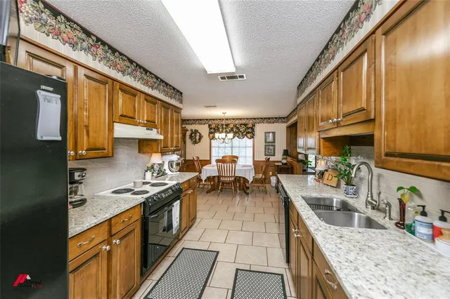 a kitchen with stainless steel appliances granite countertop a stove a sink and a refrigerator