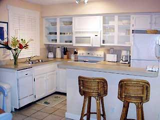 921 Center Street, Unit 1 Key West, FL 33040 - Photo 5 of 7 a kitchen with stainless steel appliances granite countertop a sink a oven a dining table and chairs with wooden floor