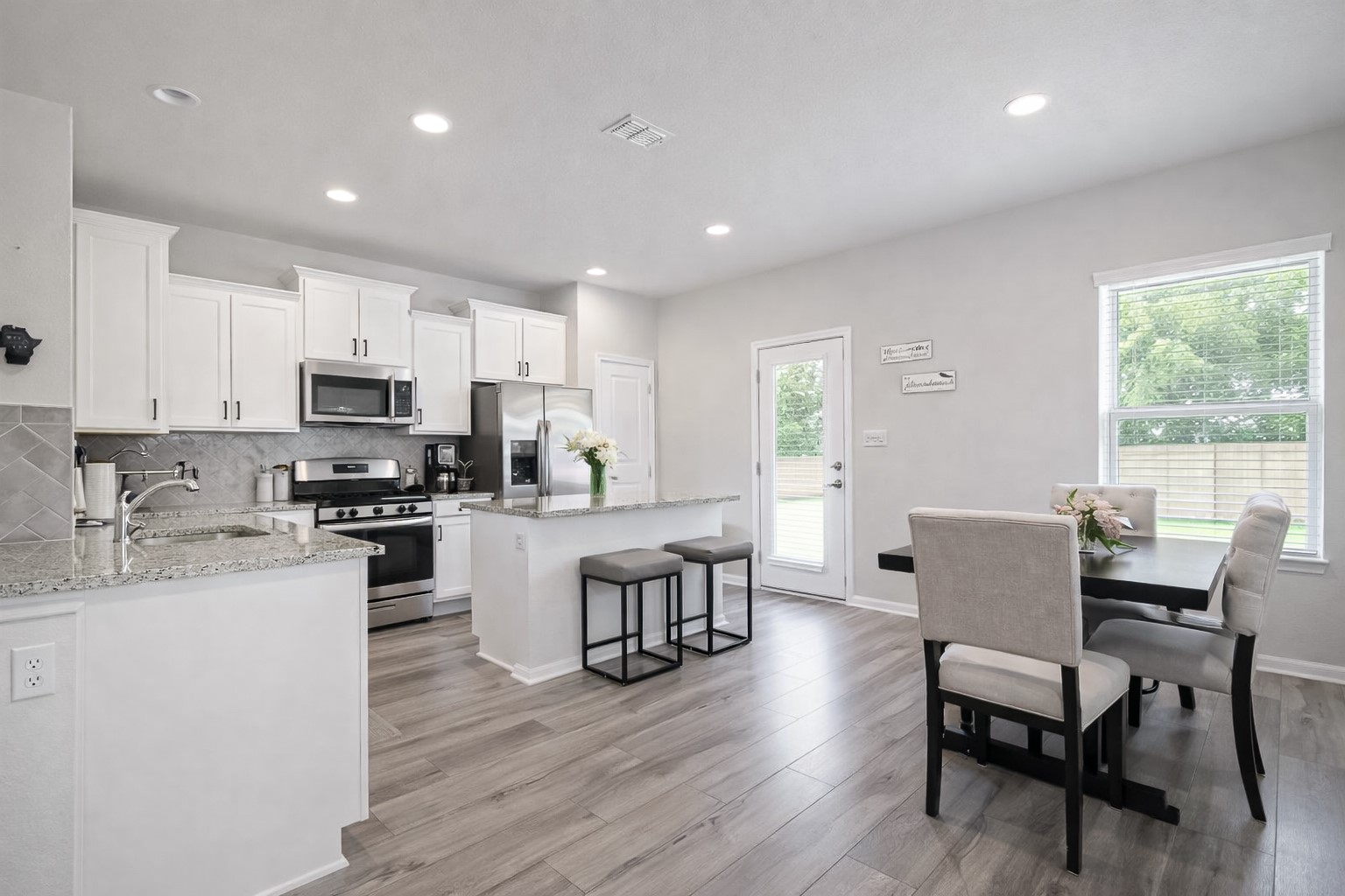 940 Paddock Lane Georgetown, TX 78626 - Photo 11 of 32 Bright kitchen and dining area featuring light wood-finish flooring, white cabinetry, stainless steel appliances, and recessed lighting