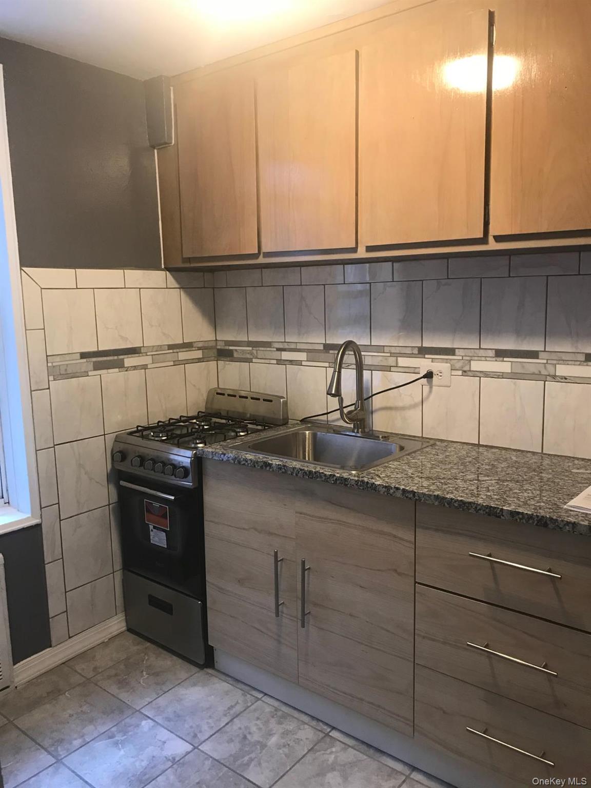 1332 Metropolitan Avenue, Unit 2A Bronx, NY 10462 - Photo 4 of 15 a kitchen with stainless steel appliances granite countertop a sink a stove and cabinets