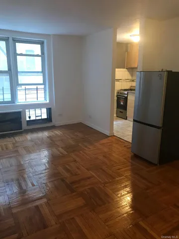 an empty room with wooden floor and windows with curtains