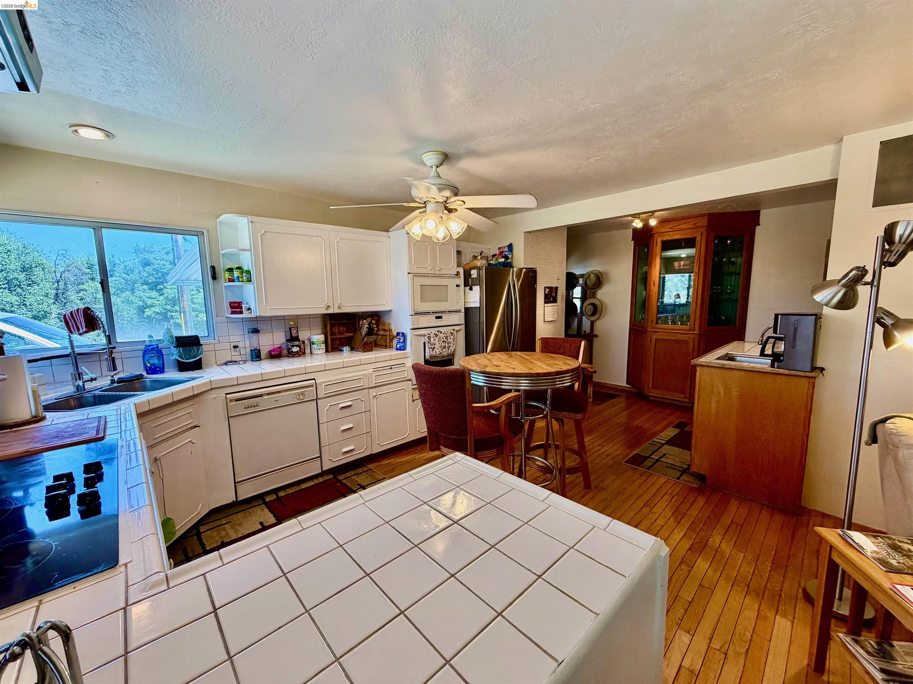 18195 Wards Ferry Road Sonora, CA 95370 - Photo 67 of 67 Kitchen featuring white cabinetry, white tile countertops, a built-in oven, and a dishwasher